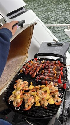 a person grilling shrimp and pineapple skewers on a boat