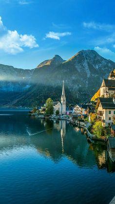 a small town on the shore of a lake with mountains in the background and blue sky