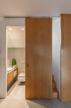 an open door leading to a bathroom with a sink and toilet in the back ground