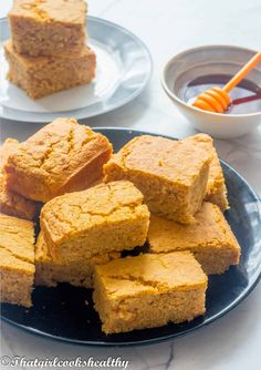 several pieces of cornbread sitting on a plate next to a bowl of dipping sauce