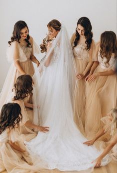 bridesmaids helping the bride put on her wedding dress