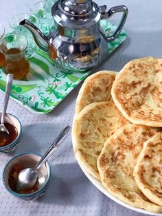 some pancakes are on a plate with syrup and tea next to it, along with other dishes