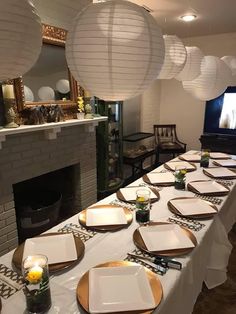 a long table is set with plates and place settings in front of a fire place