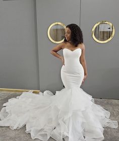 a woman in a white wedding dress standing next to a gray wall with gold trim