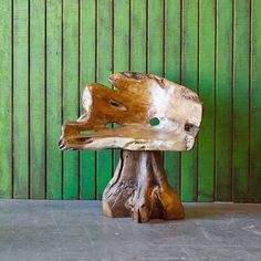 a piece of wood sitting on top of a cement floor next to a green wall