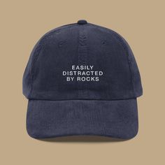 Let your hat reveal your true passion for rocks, because who can resist a good rock when they see one? Elevate your style with this embroidered vintage cap that proudly proclaims your love for the earth's treasures. Crafted meticulously from premium 100% cotton corduroy, this cap ensures a gentle feel against your skin, just like the smooth surface of your favorite rock. Its timeless design features an adjustable strap with a gold-colored buckle, guaranteeing a fit so perfect that not even the a Easily Distracted By Rocks, Rock Hat, Vintage Hats For Women, Funny Baseball Hat, Vintage Baseball Hats, Embroider Ideas, Baseball Humor, Baseball Caps, Funny Hats