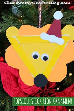 a popsicle stick lion ornament hanging from a christmas tree with the words popsicle stick lion ornament on it