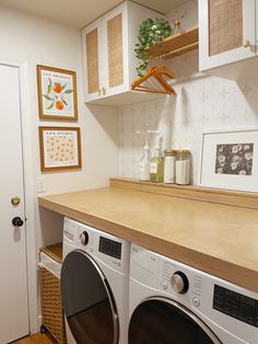 a washer and dryer in a small room with white cabinets on the wall