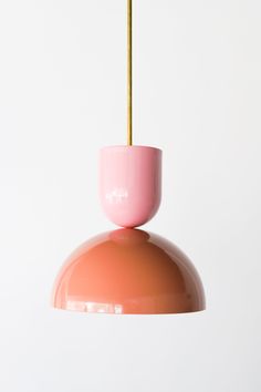 a pink and gold light hanging from a ceiling fixture with a white wall in the background