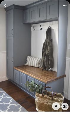 a wooden bench sitting under a coat rack next to a basket with a bag on it