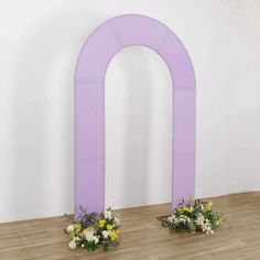 two vases with flowers are sitting on the floor in front of an arch shaped sculpture