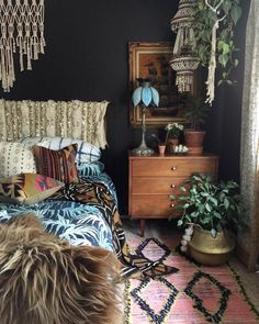 a bed room with a neatly made bed next to a dresser and potted plants