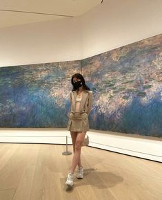 a woman standing in front of a large painting