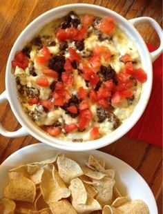 two bowls filled with food sitting on top of a wooden table next to a bowl of chips