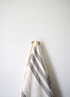 a black and white striped towel hanging on a wooden hanger against a white wall