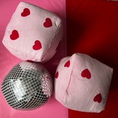 two pillows and a disco ball on a red and pink background with heart shaped cushions