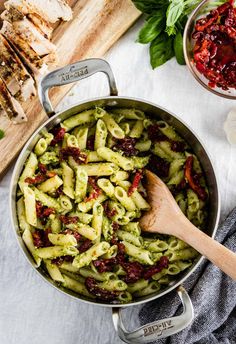 pasta with pesto sauce in a pan next to sliced chicken