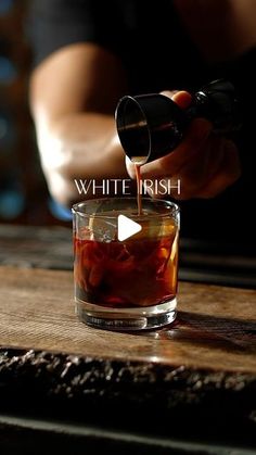 a person pouring something into a glass on top of a wooden table with the words white irish