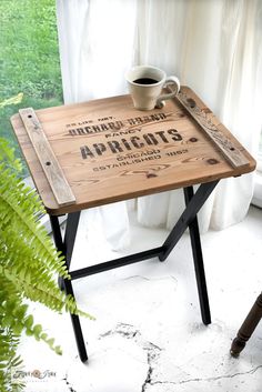 a wooden table with a coffee cup on it next to a potted plant and window