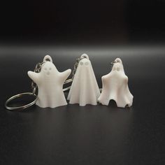 three white ghost key chains on a black surface