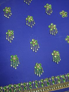 many green and white brooches are on a blue cloth with gold trimming