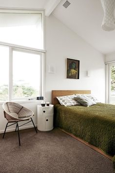 a bedroom with a bed, chair and large window in it's center area