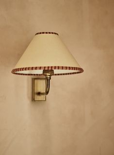 a lamp is on the wall next to a light fixture with a white and red striped shade