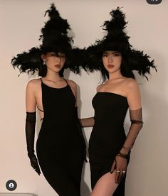 two women in black dresses and hats standing next to each other with their hands on their hips