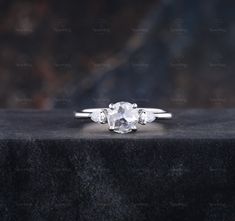 an engagement ring with three stones in the middle on top of a black stone surface