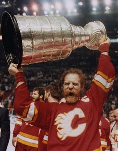 a hockey player holding up a trophy in front of an audience at a sporting event