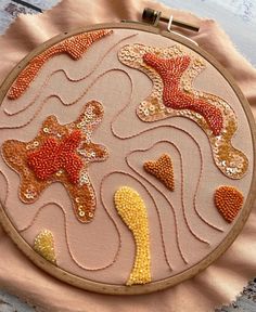 a hand embroidered starfish and seahorse design on a pink fabric with gold sequins