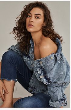 a woman sitting on the ground wearing jeans