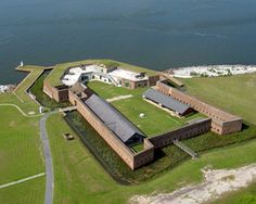 an aerial view of a large building with grass on the roof and water in the background