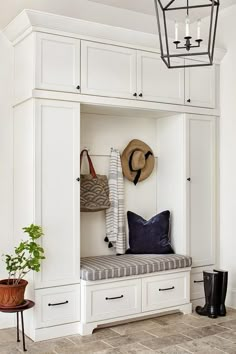 a bench with a cushion and hat on it in front of some white cupboards