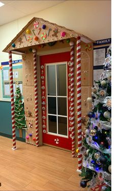 a decorated christmas tree in front of a red door with candy canes on it