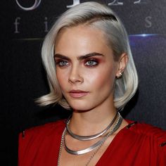 a woman with blonde hair and blue eyes wearing a red dress is posing for the camera