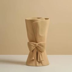 a beige vase with a bow on the side