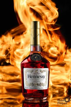 a bottle of hennesy sitting on top of a table in front of fire