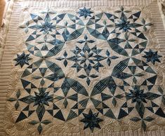 a quilted table topper with blue stars on it and an intricate design in the center