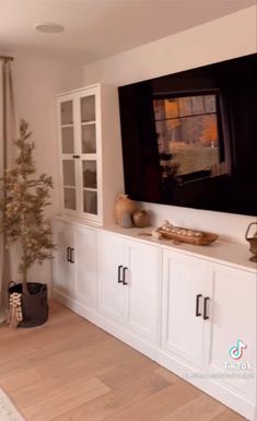 a living room with white cabinets and a large tv mounted on the wall above it