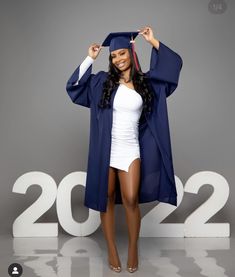 a woman wearing a graduation cap and gown standing in front of a sign that reads 2012