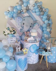 an elephant themed baby shower with blue and silver balloons on the wall next to it