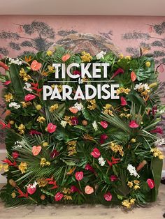 a sign that says ticket to paradise surrounded by flowers and leaves in front of a pink wall