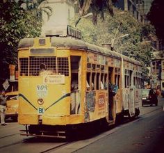 an old yellow trolley car is traveling down the street