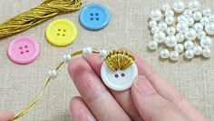 a hand holding a button and some beads