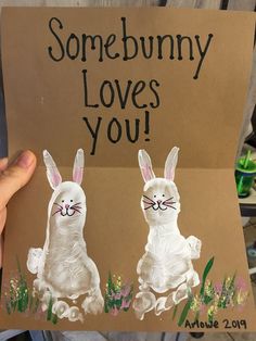 someone is holding up a card with two rabbits painted on it that says, some bunny loves you