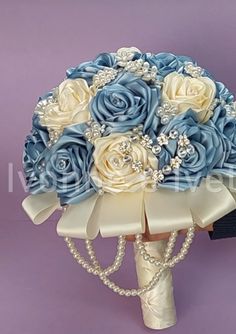 a bridal bouquet with blue roses and pearls on the bottom is sitting against a purple background