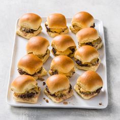 mini sliders with cheese and meat are on a white plate, ready to be eaten