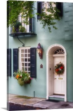 a blue building with shutters and flowers in the window boxes on the front door