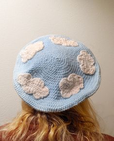 the back of a woman's head wearing a crocheted hat with clouds on it